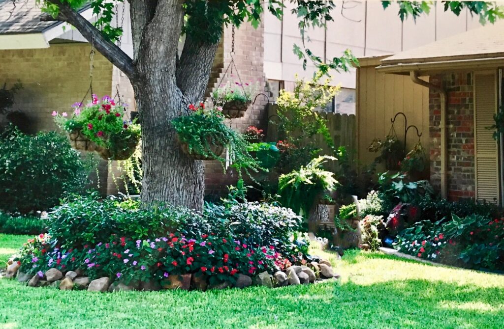 Beautiful residential landscaped front yard with flowers, hanging baskets, ferns and green plants